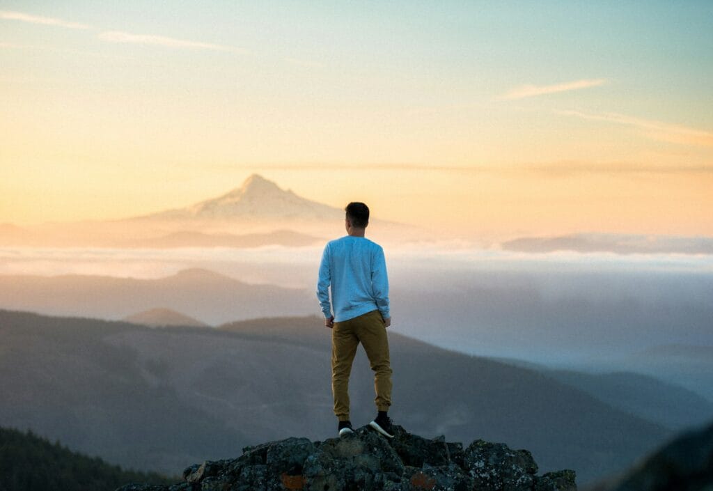 Picture of a man at the top of a mountain observing the view
