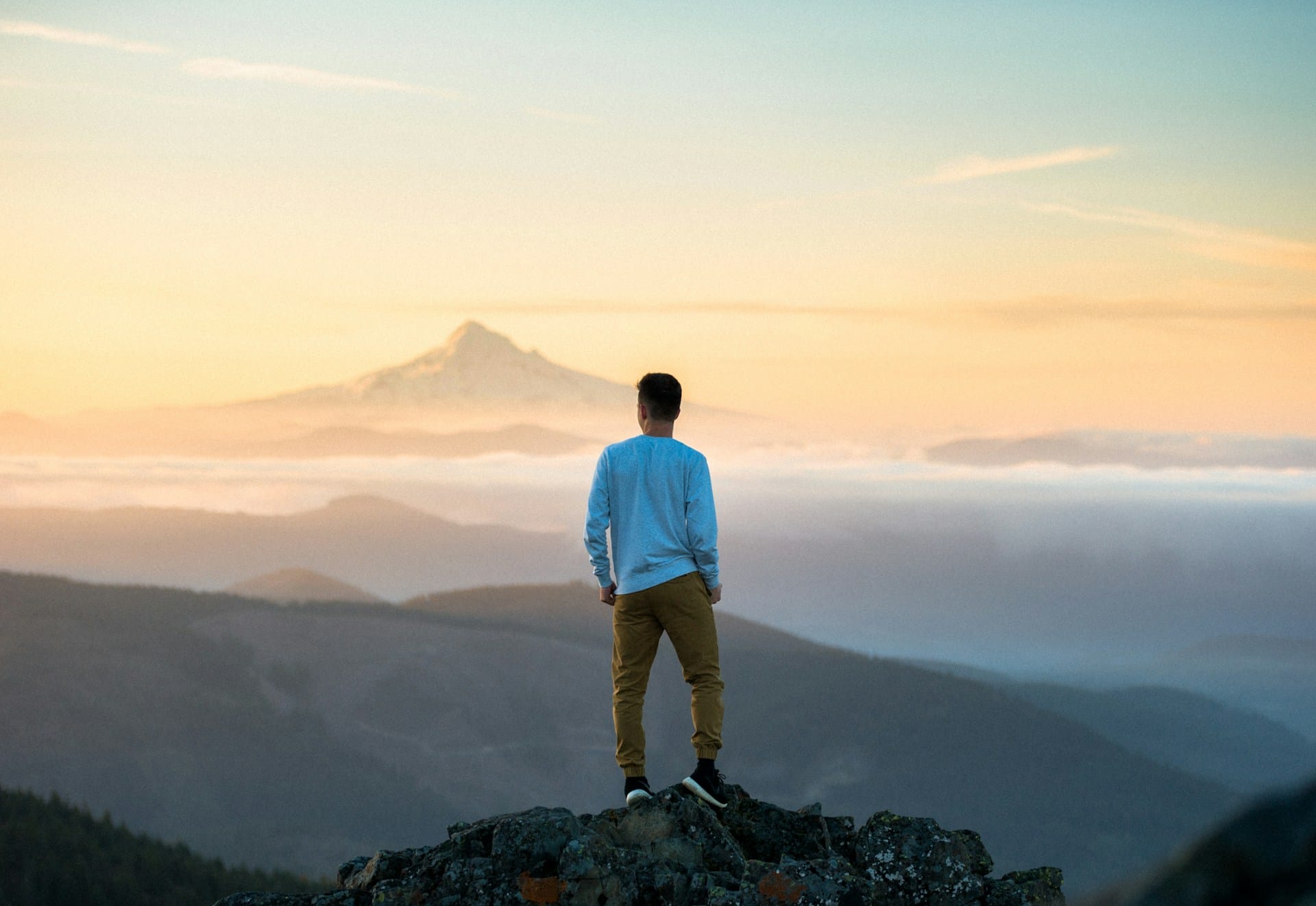 Picture of a man at the top of a mountain observing the view